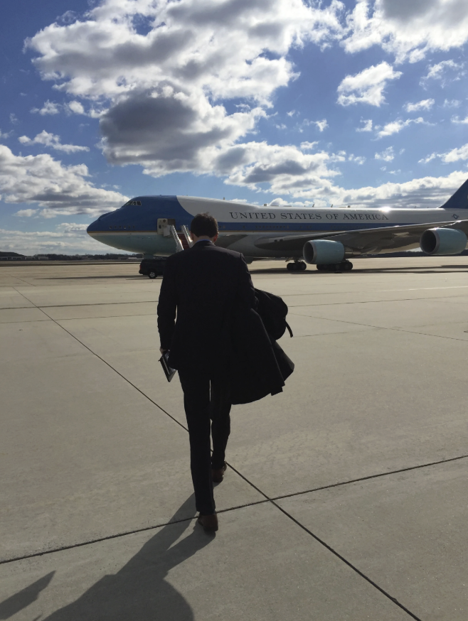A person heads toward Air Force One under a sunny sky with scattered clouds.